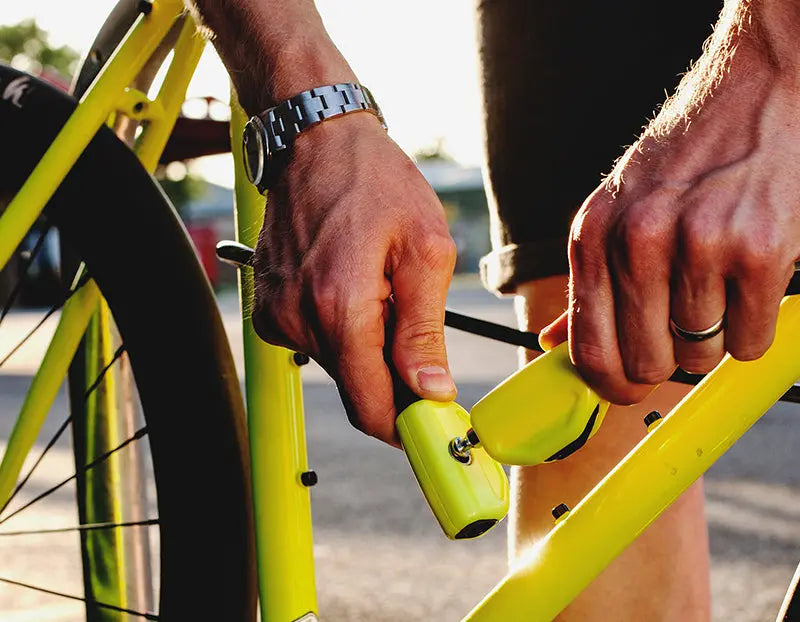man locking the front wheel and frame of his bicycle with a hiplok pop wearable cable lock