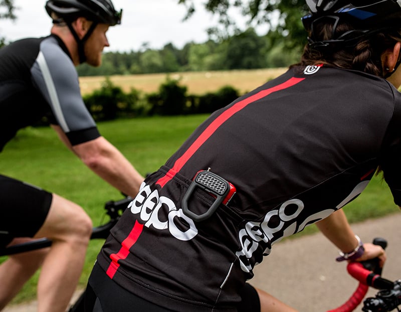 women riding a road bicycle with a hiplok fx clipped to the rear pocked of her cycling jersey