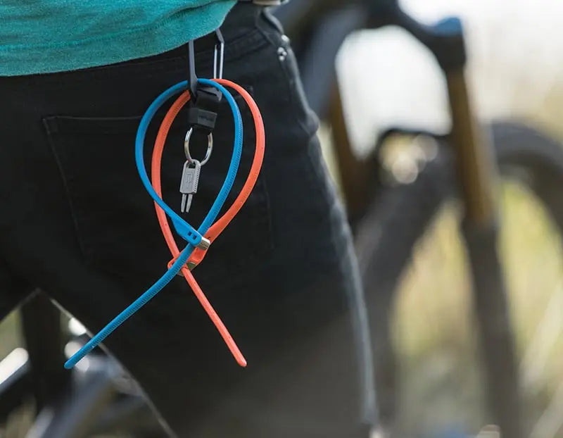 mountain biker pushing bike up hill with a key clip attached to the belt loop of his jeans holding two z loks