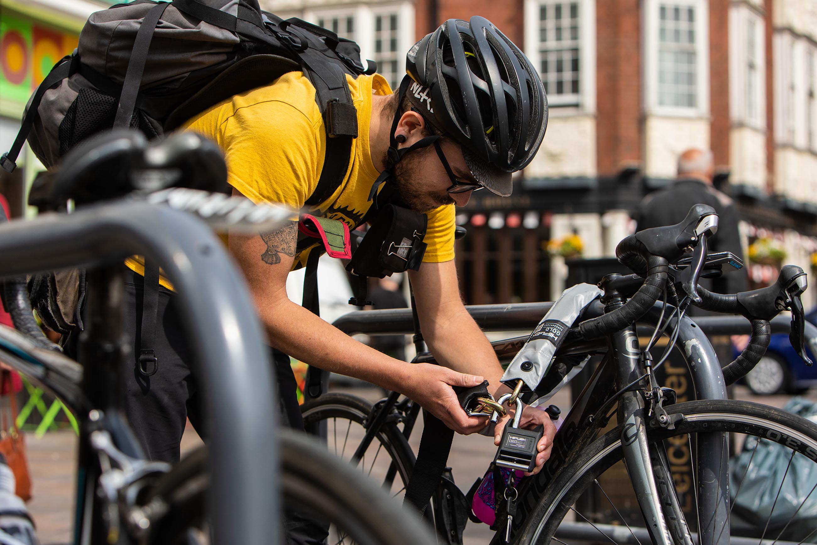 man in urban area locking bike to metal bike lock with chain lock
