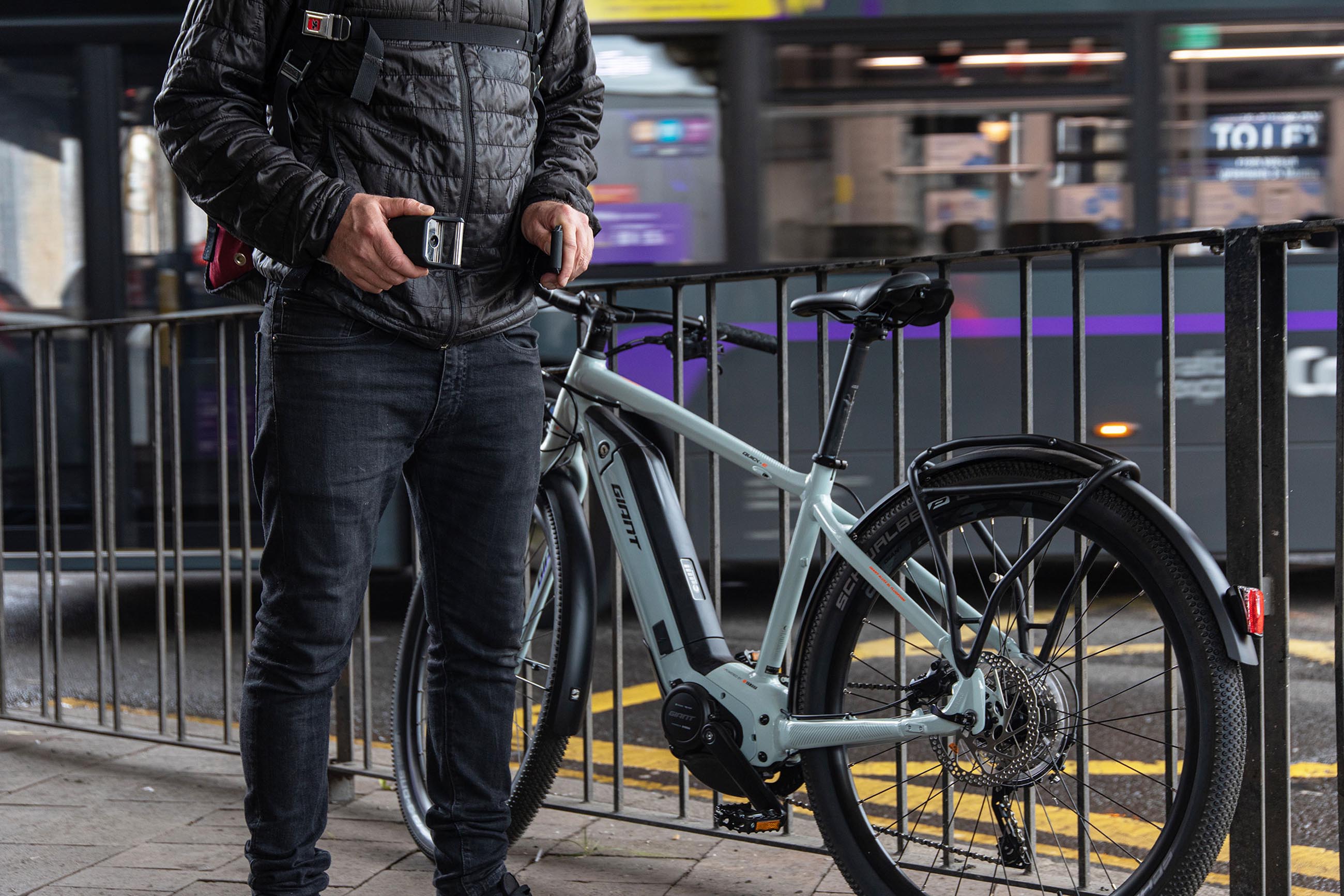 e bike lent against railing man un straping wearble chain lock from waist