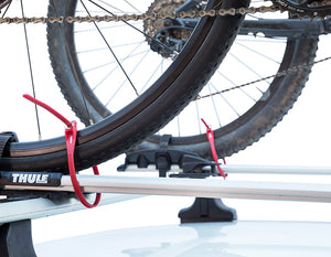 rear wheels of two bicycles attached to a roof rack on the roof of a car with z loks locking wheels to the rack
