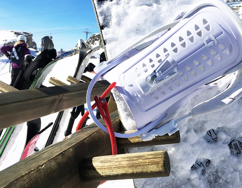 snowboard covered in snow slotted into snowboard rack locked with a z lok