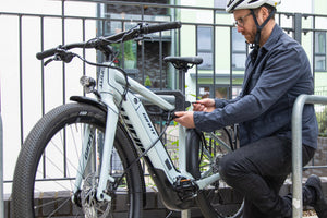 man locking electric bike to metal bike rack with d lock and steel accesories cable