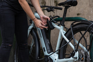 women locking electric bike to metal bike rack with d lock and steel accesories cable