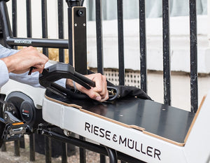 man locking EDX chain lock and d lock to cargo bike on a fence