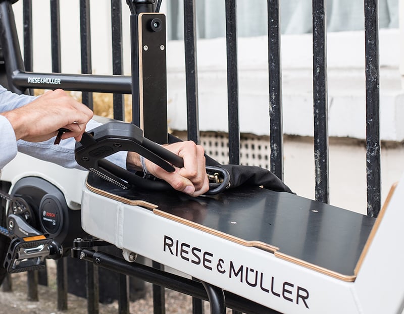 man locking EDX chain lock and d lock to cargo bike on a fence