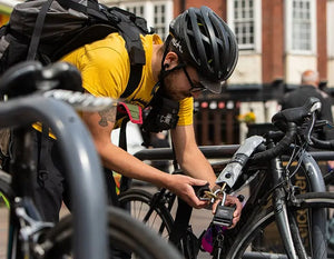 man in urban area locking bike to metal bike lock with chain lock