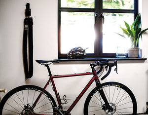 bike in a house lent against a wall with a long heavy duty chain lock hooked to the wall
