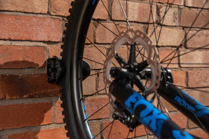 Mountain Bike front wheel stored in JAW compact bike rack vertically against brick wall outdoors