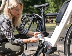 women locking electric bike to metal bike rack with a chain lock