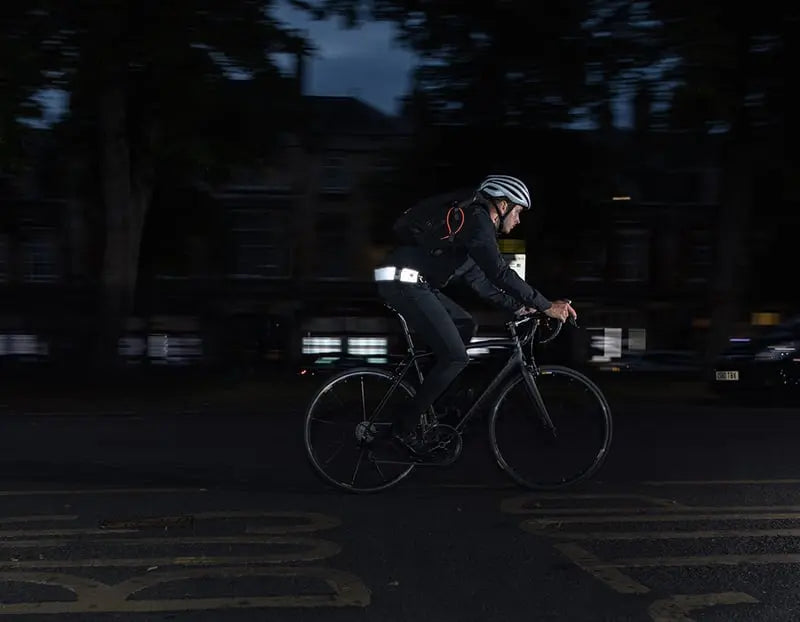 man riding on a road in the dark with wearble reflective chain lock around waist