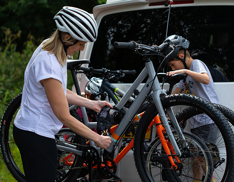 women and child locking bikes to bike rack on the back of a van with heavy duty chain lock
